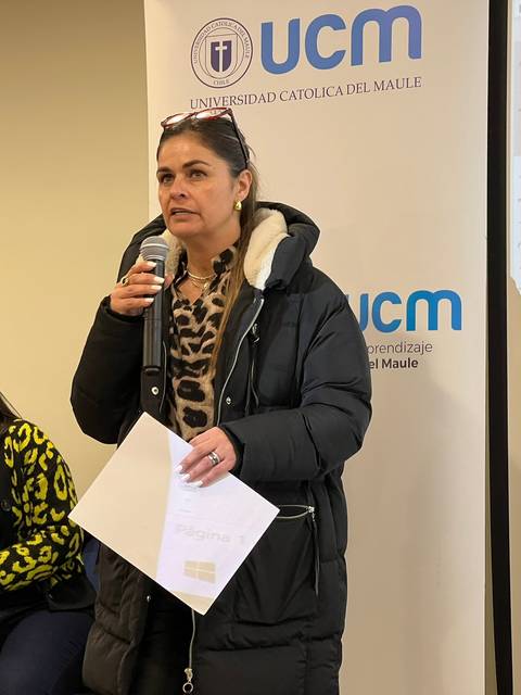 Una mujer habla en un evento mientras otra persona la escucha atentamente.