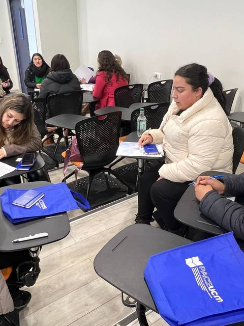 Un grupo de mujeres se reúne en un aula para trabajar en grupo mientras toman notas.