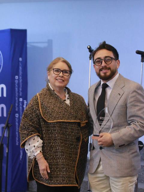 Una mujer y un hombre posan juntos, con un trofeo en la mano, en un evento formal.