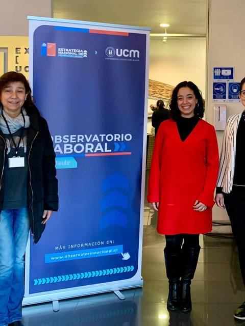 Tres mujeres posan junto a un banner del Observatorio Laboral en un ambiente institucional.