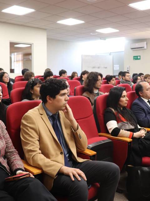 Una audiencia atenta sentada en un salón de conferencias.