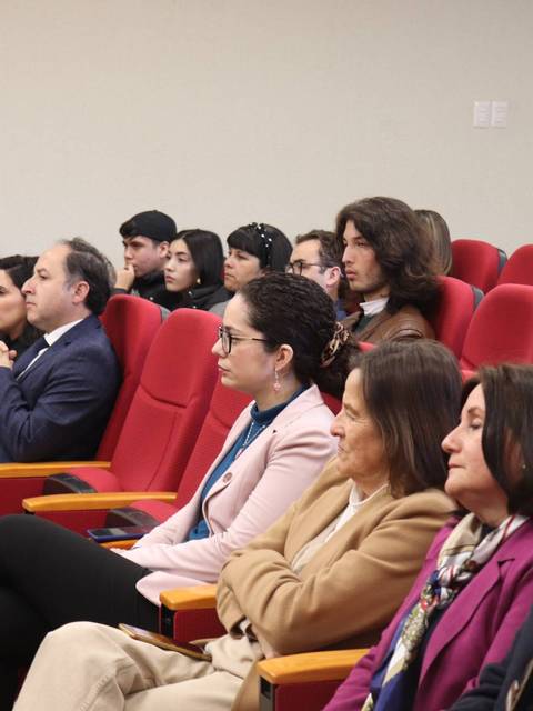 Un grupo de personas sentadas en un auditorio durante un evento.
