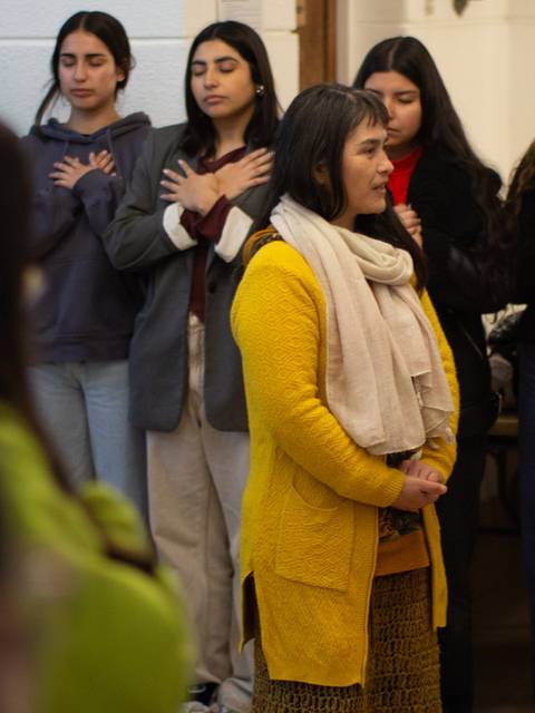 Un grupo de personas participa en una actividad de reflexión con las manos en el corazón.