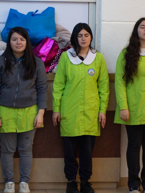 Un grupo de jóvenes en uniforme de trabajo se encuentran alineadas en un pasillo.