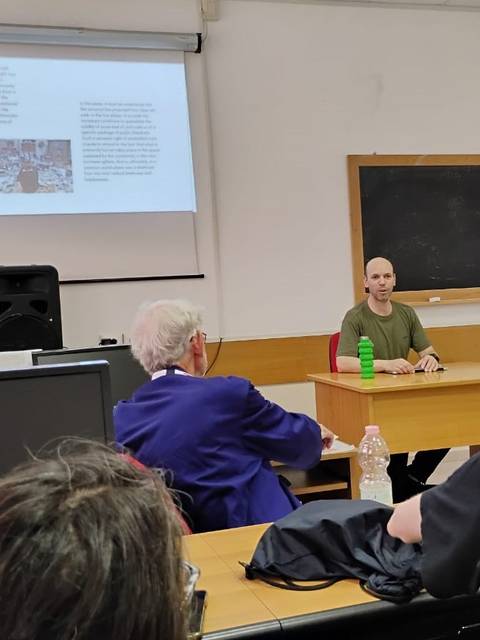 Un hombre presenta en un aula mientras los asistentes lo escuchan atentamente.