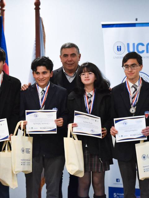 Grupo de estudiantes premiados en un evento académico con medallas y certificados.