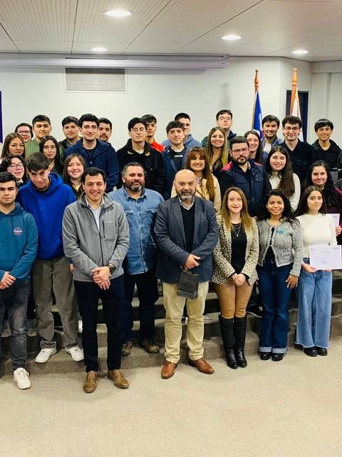 Un grupo amplio de estudiantes y profesores posan juntos en un evento formal.