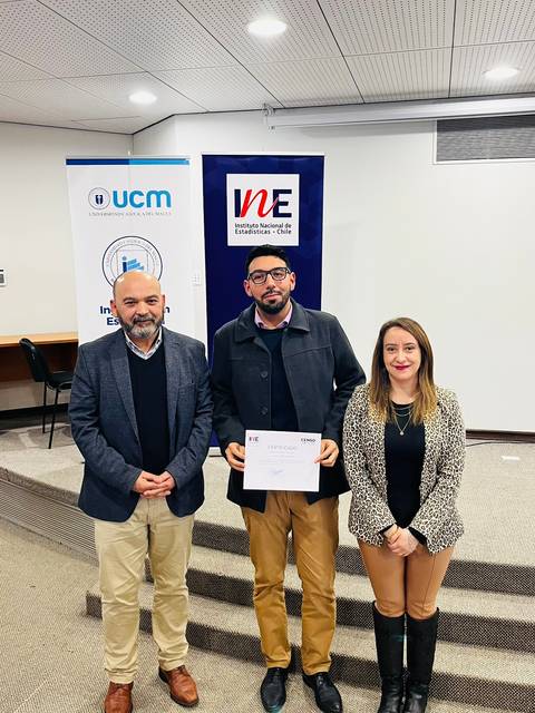 Un grupo de tres personas posando en un evento formal, sosteniendo un certificado.