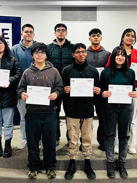 Un grupo de estudiantes sonrientes sostiene certificados en una ceremonia de entrega.
