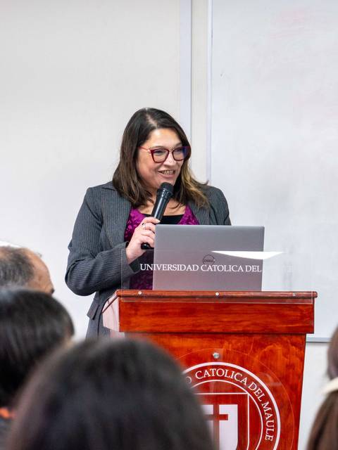 Una mujer está hablando desde un podio en un evento universitario.