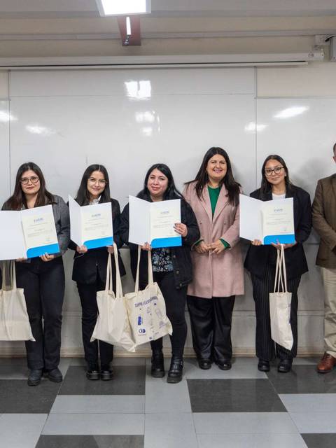 Un grupo de estudiantes posando con sus certificados en un aula.