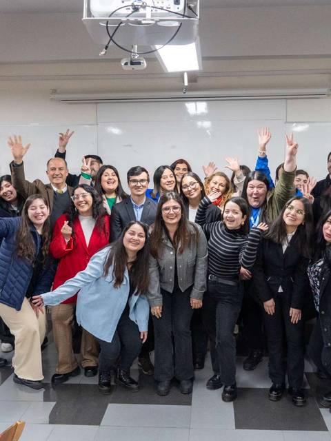 Un grupo de personas sonrientes y felices posando juntas en un aula.