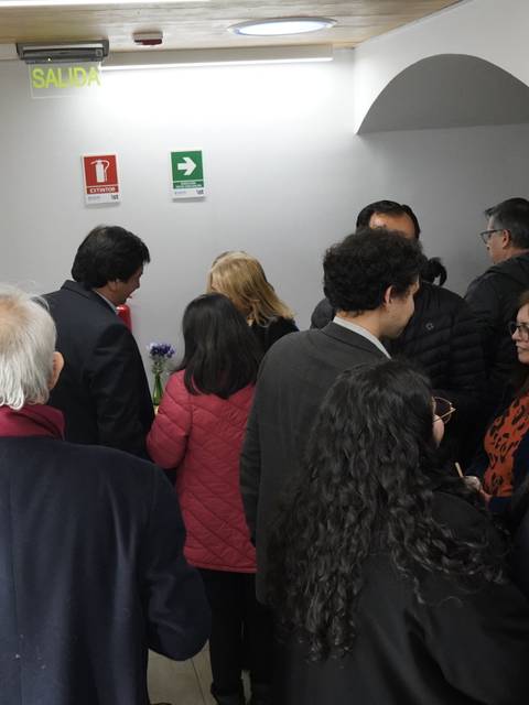 Un grupo de personas conversando en un pasillo con obras de arte en las paredes.