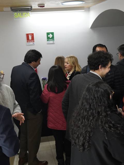 Un grupo de personas conversando en un pasillo con pinturas en las paredes.