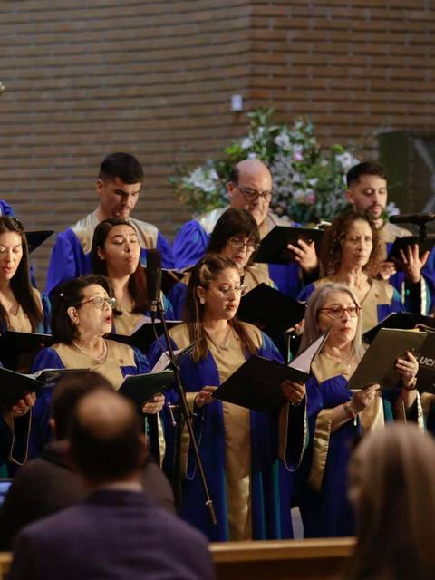 Un coro de cantantes vestidos con túnicas azules está interpretando en una ceremonia en un lugar de culto.