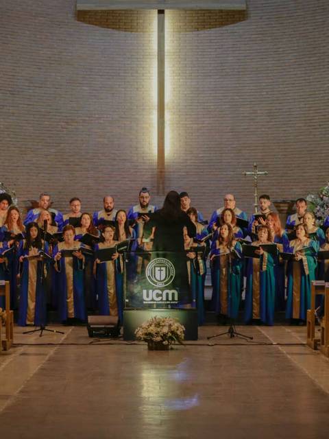 Un coro se presenta en un escenario frente a una congregación en una iglesia.