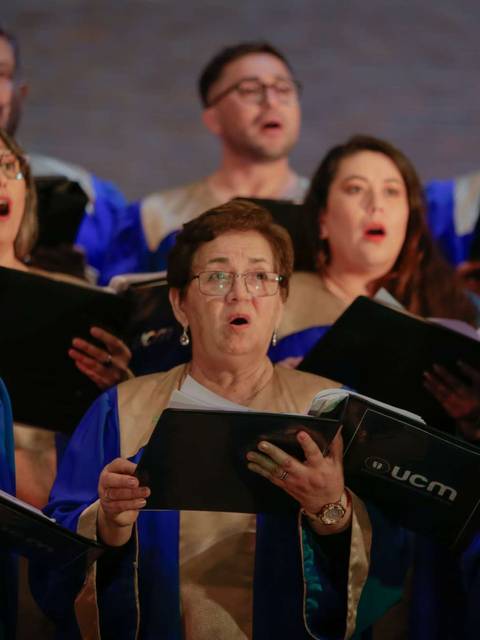 Un coro de personas cantando con vestimentas azules y doradas en un evento.