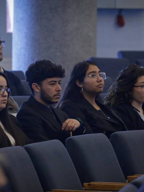 Un grupo de personas sentadas en un auditorio prestando atención.