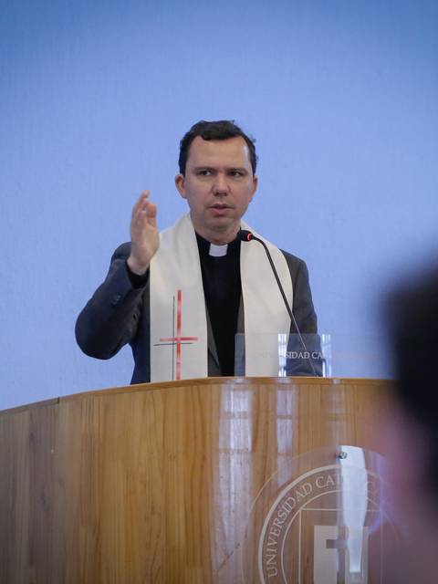 Un hombre con vestimenta religiosa habla desde un podio en un evento académico.