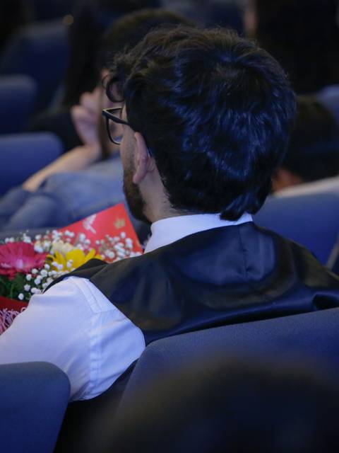 Una persona con un ramo de flores se sienta en un auditorio.