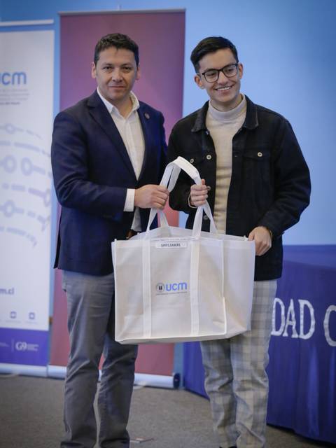 Dos hombres sostienen una bolsa en un evento formal.