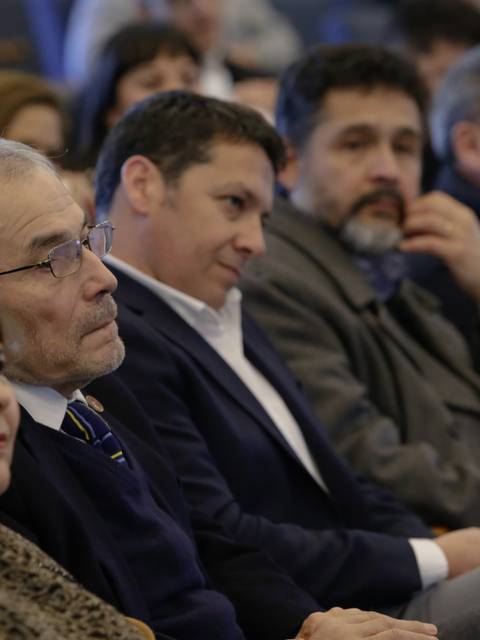 Un grupo de personas sentadas, escuchando atentamente en un evento.