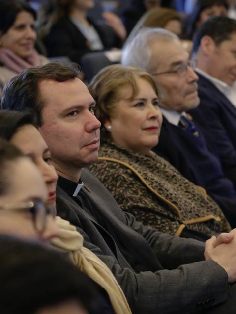 Un grupo de personas sentadas en un auditorio, prestando atención a una presentación.
