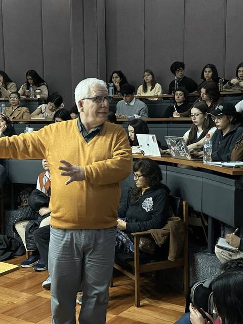 Un profesor expone ante un grupo de estudiantes en un aula universitaria.