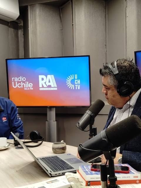 Dos hombres conversan durante una transmisión en vivo en un estudio de radio.