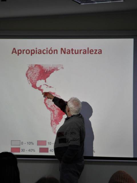 Un hombre señala un mapa que muestra la apropiación de la naturaleza en América Central y del Sur.