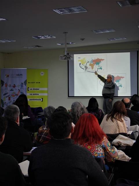 Un profesor está dando una presentación frente a un grupo de estudiantes en un aula.