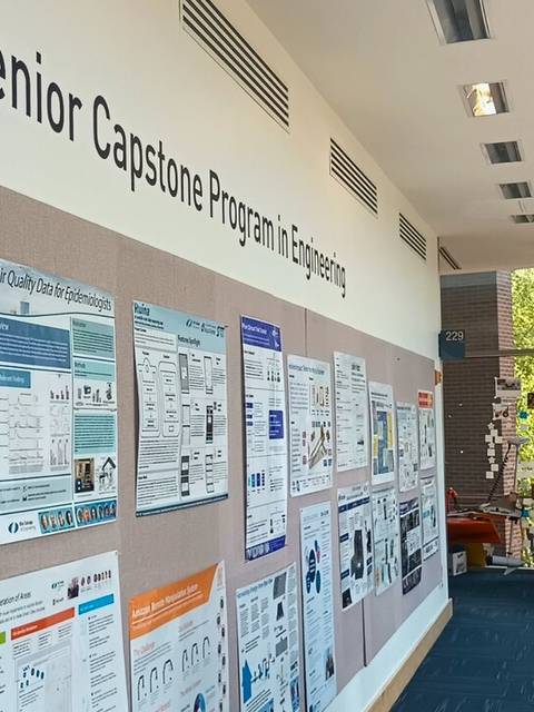 Un hombre observa una serie de carteles informativos en una presentación de proyectos de ingeniería.