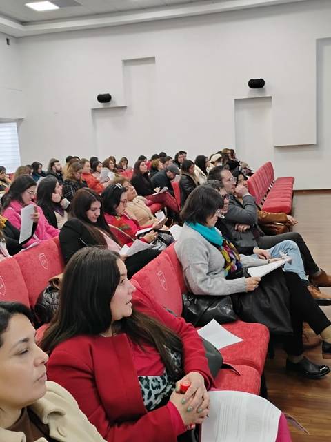 Una sala llena de personas escuchando a una oradora en un evento.