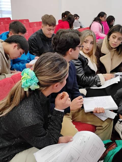 Un grupo de estudiantes conversando y trabajando en un aula.