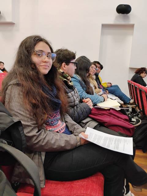Un grupo de jóvenes sentados en un auditorio, esperando un evento.