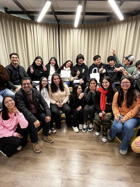 Un grupo de personas sonríen y hacen señales de paz en un ambiente acogedor.