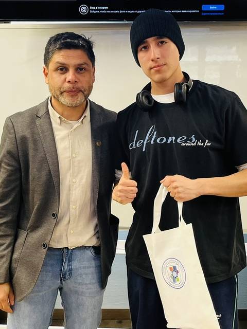 Dos hombres posan juntos, uno de ellos hace una señal de pulgar hacia arriba.