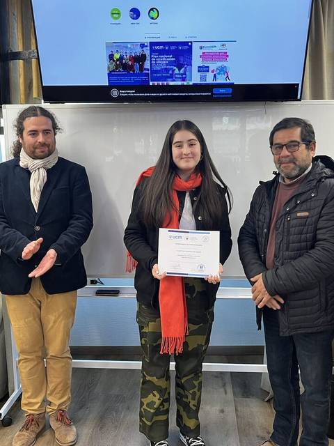 Un grupo de personas se reúne para celebrar la entrega de un certificado a una joven destacada.