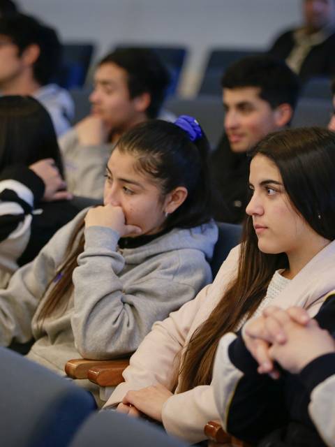Un grupo de jóvenes atentos durante una presentación en una sala.