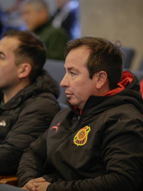 Un grupo de personas sentadas en una reunión, prestando atención a lo que ocurre frente a ellos.