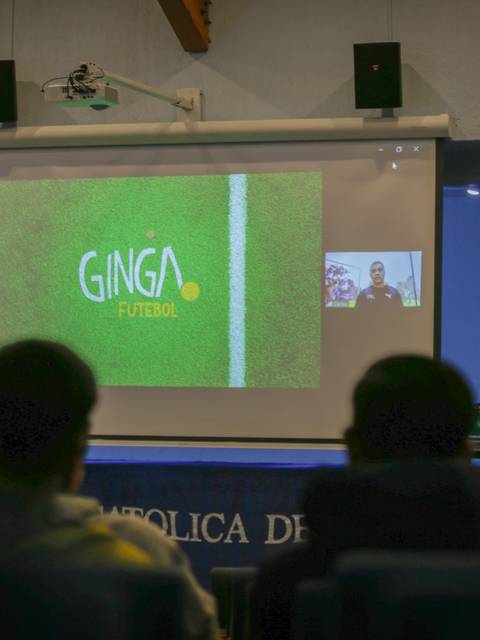 Una presentación en una sala con una pantalla que muestra el logo de Ginga Fútbol.
