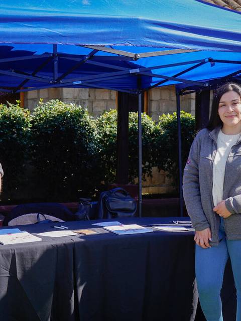 Dos personas sonrientes se encuentran en un stand al aire libre, promoviendo Coexca S.A.