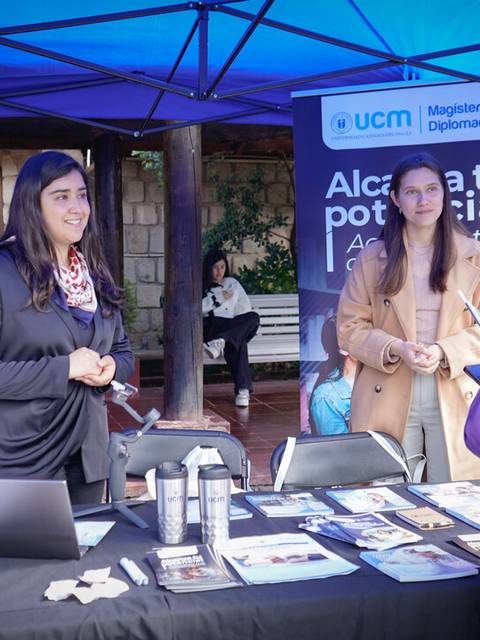 Una feria donde personas interactúan en un stand informativo sobre programas académicos.