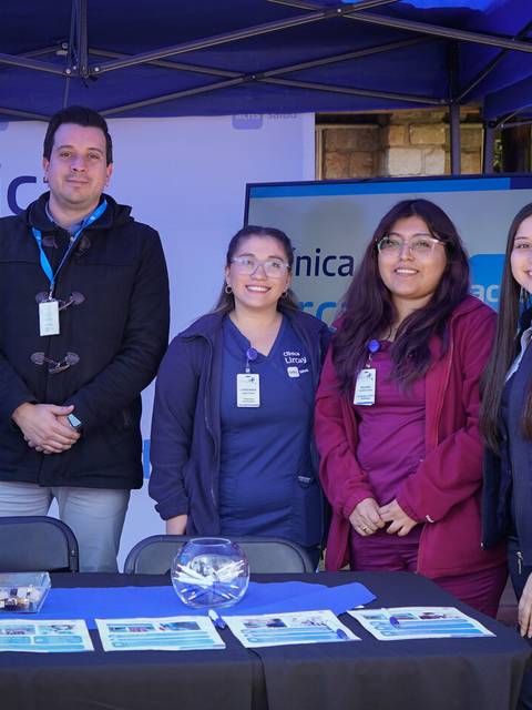 Cuatro personas posan juntas junto a una mesa con material informativo sobre la clínica.