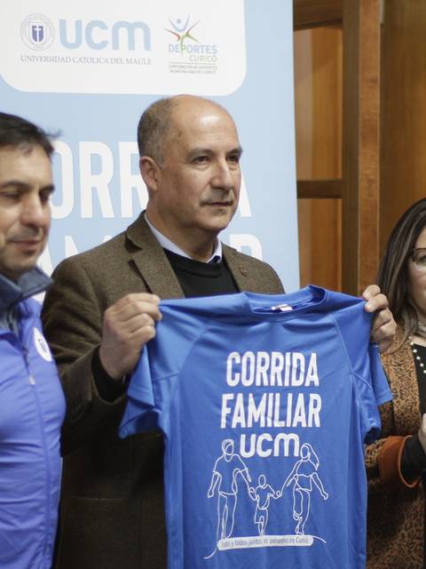Un grupo de personas sostiene camisetas azules de una corrida familiar mientras posan para la foto.