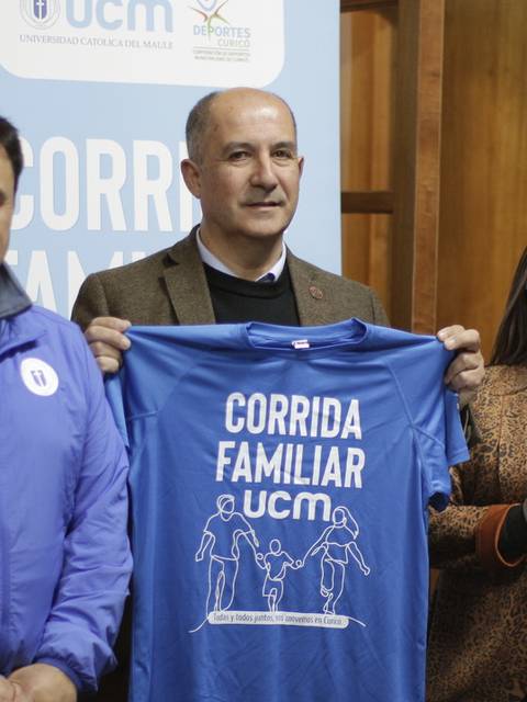Cuatro personas sosteniendo camisetas de un evento llamado 'Corrida Familiar'.