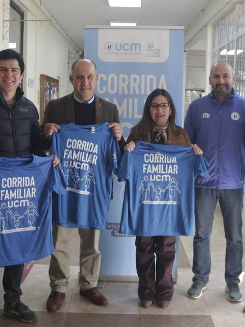 Un grupo de personas sostiene camisetas de un evento llamado 'Corrida Familiar' en un ambiente interior.