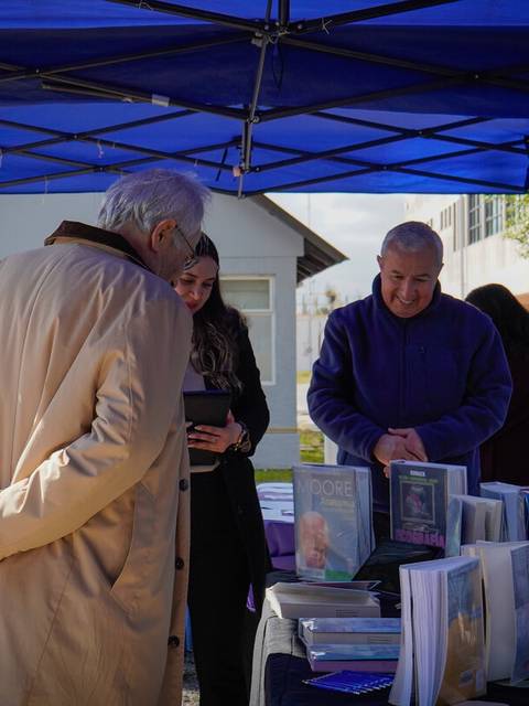 Una feria de libros donde varias personas interactúan en un stand.