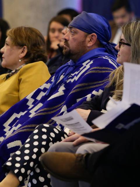 Un grupo de personas sentadas en un evento, algunas llevando vestimenta tradicional.