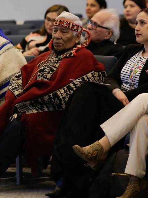 Un grupo de personas sentadas en una sala, algunas con vestimenta tradicional.